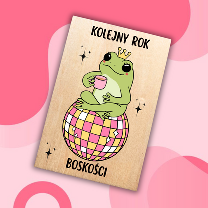 drewniana kartka urodzinowa z żabą w koronie siedzącą na kuli dyskotekowej 