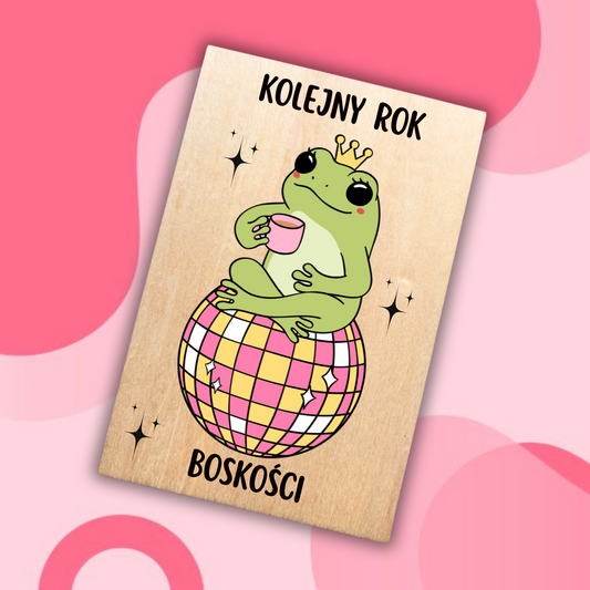 drewniana kartka urodzinowa z żabą w koronie siedzącą na kuli dyskotekowej 